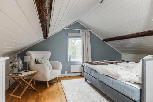 a attic bedroom with a bed and a chair at Rustic Nordic Getaway by the Sea in Axmar