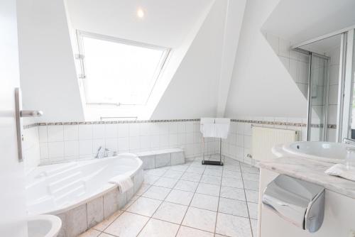 a white bathroom with a tub and a sink at Parkhotel Bad Homburg in Bad Homburg vor der Höhe