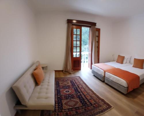 a bedroom with two beds and a couch and a window at Casa do Vale in São Vicente