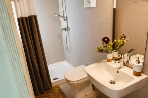 a bathroom with a sink and a toilet and a shower at Luxury Suite in Heerewaarden