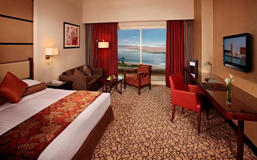 a hotel room with a bed and a desk at Khalidiya Palace Rayhaan by Rotana, Abu Dhabi in Abu Dhabi