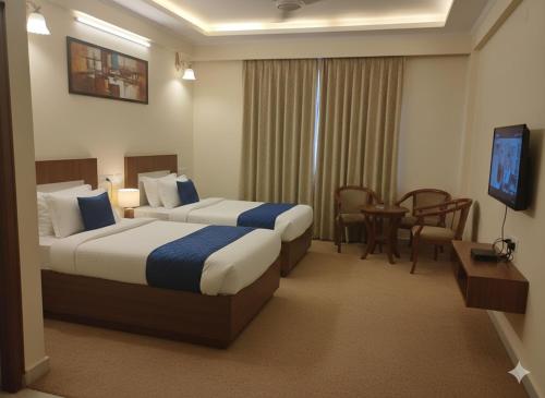 a hotel room with two beds and a television at AR Residency Tnagar Chennai in Chennai