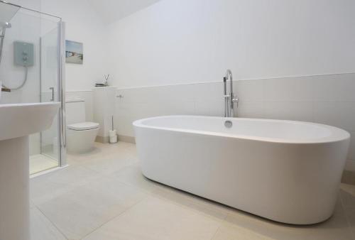 a white bathroom with a tub and a sink at 2 Bed in Leiston oc-cqa in Theberton