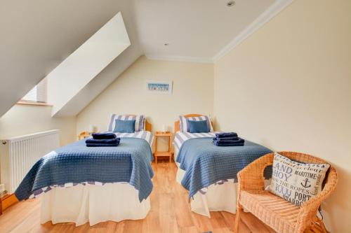 a bedroom with two beds and a chair at 2 Bed in Blakeney oc-1558 in Blakeney