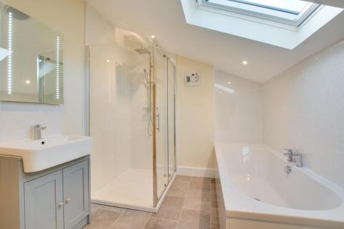 a bathroom with a shower and a sink and a tub at 3 Bed in Sheringham oc-2170 in Sheringham