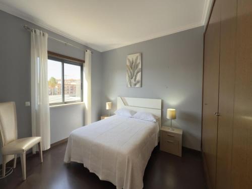 a white bedroom with a bed and a window at Terracos Da Meia Praia in Meia Praia