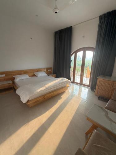 a bedroom with a bed and a large window at The Tarai Pilibhit in Kālīnagar