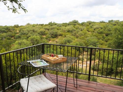 a table on a balcony with a view of a forest at Meulensrus in Hoedspruit