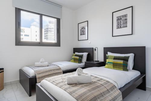 three beds in a room with white walls and windows at Hinoki 2-Bedroom Apartment in Larnaca