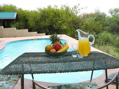 a table with a bowl of fruit and a glass of orange juice at Meulensrus in Hoedspruit
