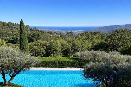 a blue swimming pool in a garden with trees at Les Hauts de la Riviera in Cabris