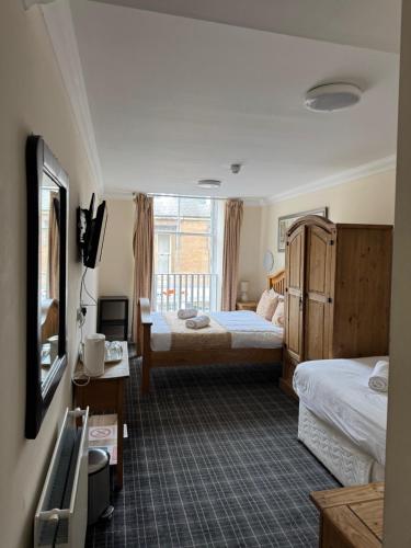 a hotel room with two beds and a television at Royal Guest House in Dingwall