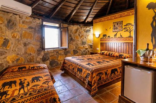 a bedroom with two beds and a stone wall at Hotel Selwo Lodge - Animal Park Tickets Included in Estepona