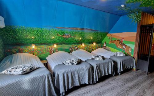 three beds in a room with a painting on the wall at Drouwenerzand Hotel in Drouwen