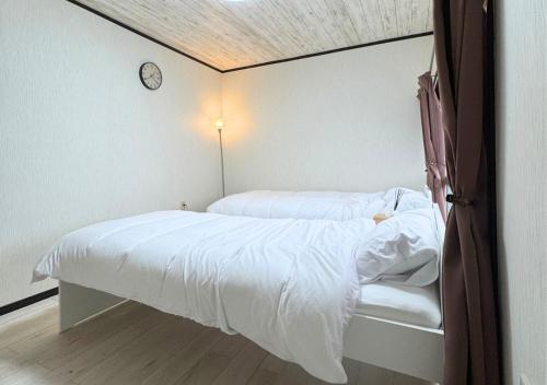 a bedroom with two beds and a clock on the wall at Nishijin Stay One in Fukuoka