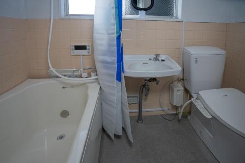 a bathroom with a tub and a sink and a toilet at cozy 3rd stay in Okayama