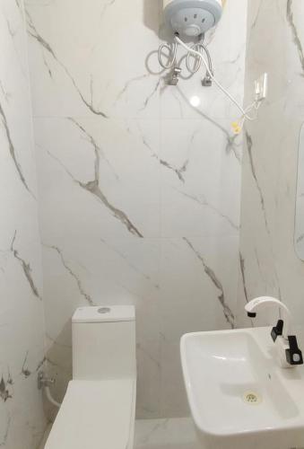 a white bathroom with a toilet and a sink at Hotel Royale Elite RK Residency in Vrindāvan