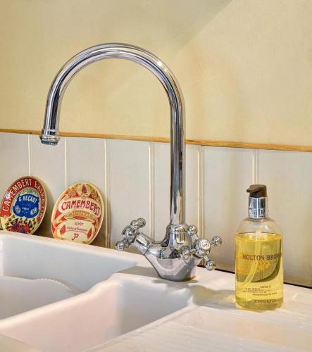 ein Waschbecken mit einer Seifenflasche neben einem Wasserhahn in der Unterkunft Alde Barn in Stonham Aspall