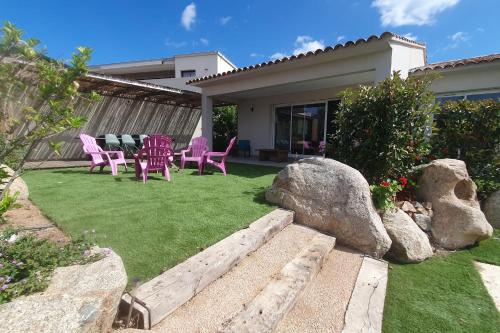 a backyard with pink chairs and a lawn with rocks at CASA VIGNA - villa T4 piscine privée in Sainte-Lucie de Porto-Vecchio
