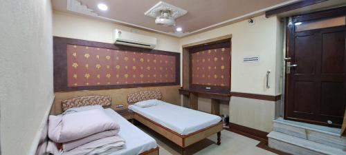 a small room with two beds and a door at Hotel Shri Shanti Niwas in Bikaner