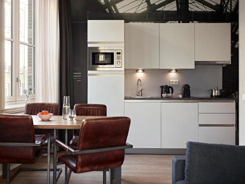 a kitchen with white cabinets and a table with chairs at YAYS Amsterdam Maritime by Numa in Amsterdam