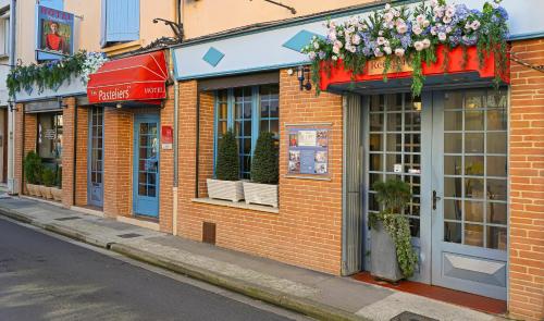 a row of stores on a street with flowers at Charming Hôtel - Les Pasteliers in Albi