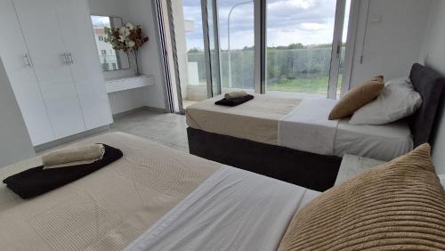 two beds in a room with a large window at Protaras Heights- Hana in Paralimni