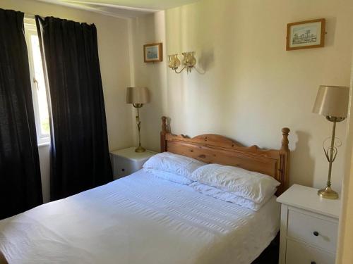 a bedroom with a bed with white sheets and a window at Bolthole in Hayle