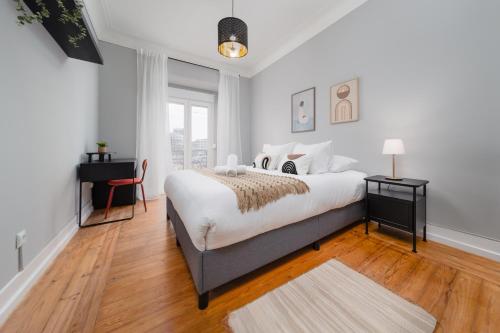 a white bedroom with a large bed and a desk at Soar Home l ENTRECAMPOS 3 l Central Comfort Stay, Fast WiFi, Steps to Metro, Near Campo Grande Park in Lisbon