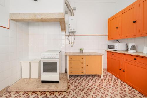 a kitchen with orange cabinets and a white stove top oven at Soar Home l ENTRECAMPOS 3 l Central Comfort Stay, Fast WiFi, Steps to Metro, Near Campo Grande Park in Lisbon