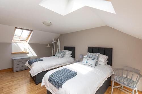 a attic bedroom with two beds and a chair at 2 Bed in Braunton oc-stabb in Braunton