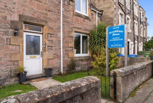 a blue sign in front of a brick house at mySTAYINN Strathblane House in Inverness