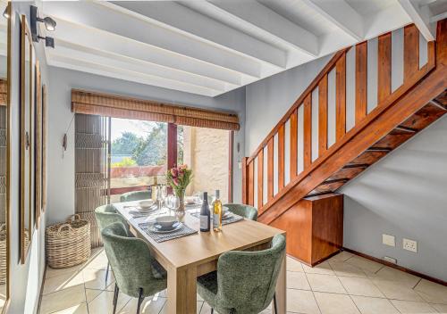 a dining room with a table and chairs and a staircase at Via Positano 95, Paulshof in Sandton