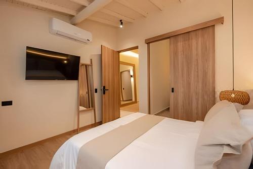 a bedroom with a white bed and a television at 2Luxury Provenza: Htd Pool, Jacuzzi, BBQ, Pool in Medellín