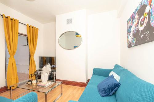 a living room with a blue couch and a glass table at Xtra Large 4 Bedroom House with Heating Sleeps 14 Near Station and ExCeL in London