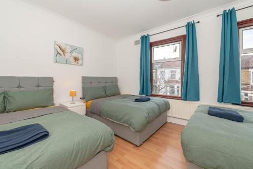 a bedroom with two beds and a window at Xtra Large 4 Bedroom House with Heating Sleeps 14 Near Station and ExCeL in London