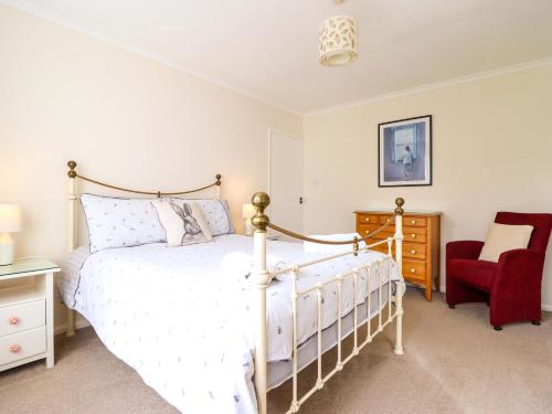 a bedroom with a bed and a red chair at Castle Cove in Abergele
