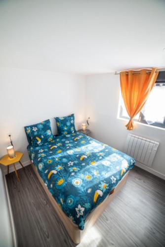 a bedroom with a bed with a blue comforter and a window at Appartement Sun GroupamaLyon Eurexpo in Meyzieu