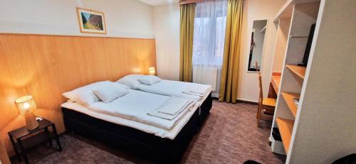 a bedroom with a bed with white sheets and pillows at Thermál Apartmanház in Komárom