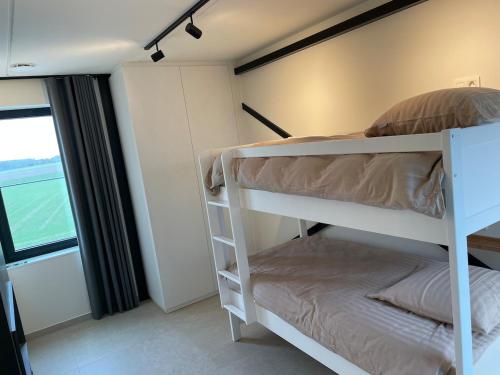 a bedroom with two bunk beds and a window at Klein Vloethemnest in Zedelgem