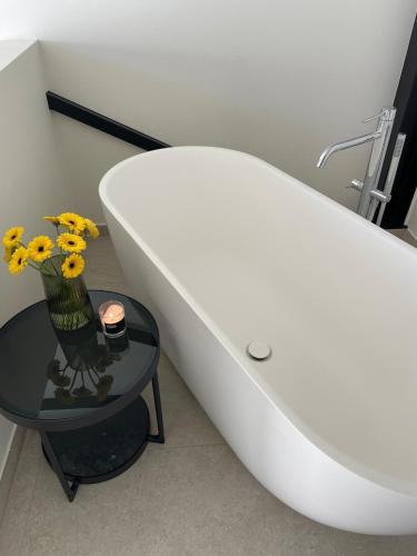 a white toilet in a bathroom with flowers on a table at Klein Vloethemnest in Zedelgem