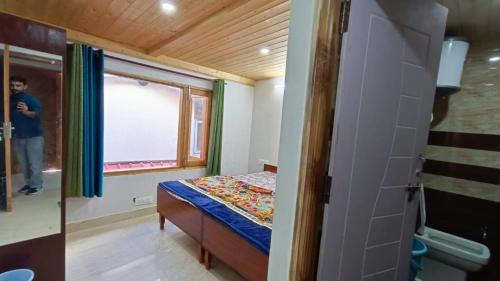 a small bedroom with a bed and a window at The Hostelers Homestay Shimla - Near ISBT, Bypass MC Parking and HPU in Shimla