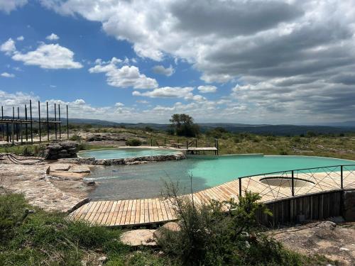 two pools of water with a wooden bridge in a field at Sauron Adventure in Cuesta Blanca