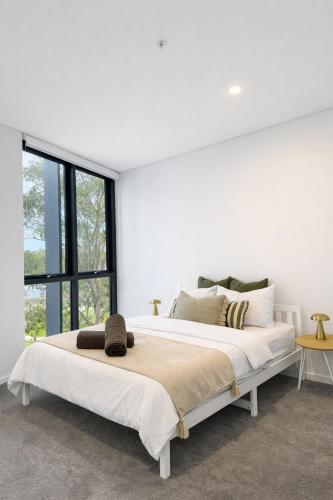 a white bedroom with a large bed with a large window at Waterfront High Rise 5 Beds 2 Car Parks in Sydney
