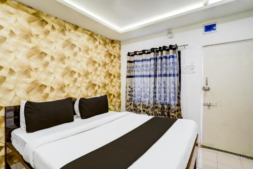 a bedroom with a white bed and a wall at Super Collection O Hingna Road in Nagpur