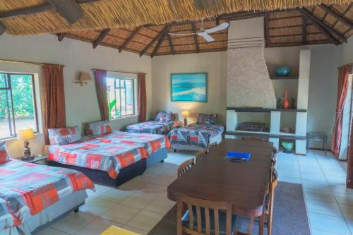 a room with three beds and a table and a dining room at Gallery Inn in Bela-Bela