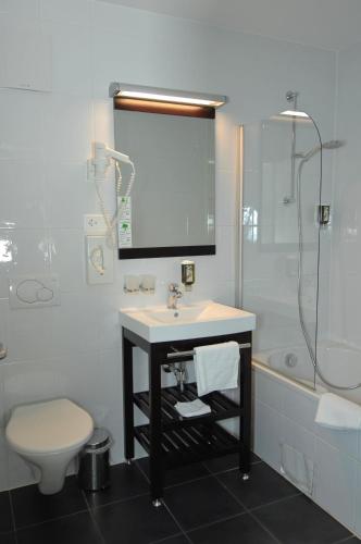 a bathroom with a sink and a toilet and a shower at Auberge de la Gare in Grandvaux