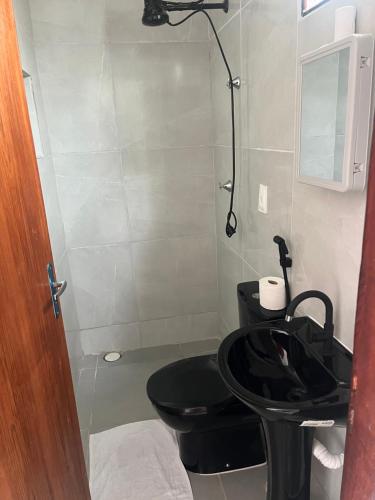 a bathroom with a black toilet and a sink at Pousada Água Viva in Maceió