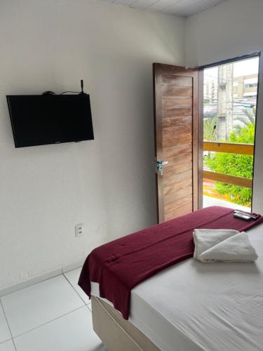 a bedroom with a bed with a television on the wall at Pousada Água Viva in Maceió