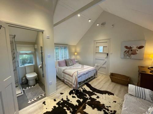 a bedroom with a bed and a cow painting on the wall at The Hen House in North Huish
